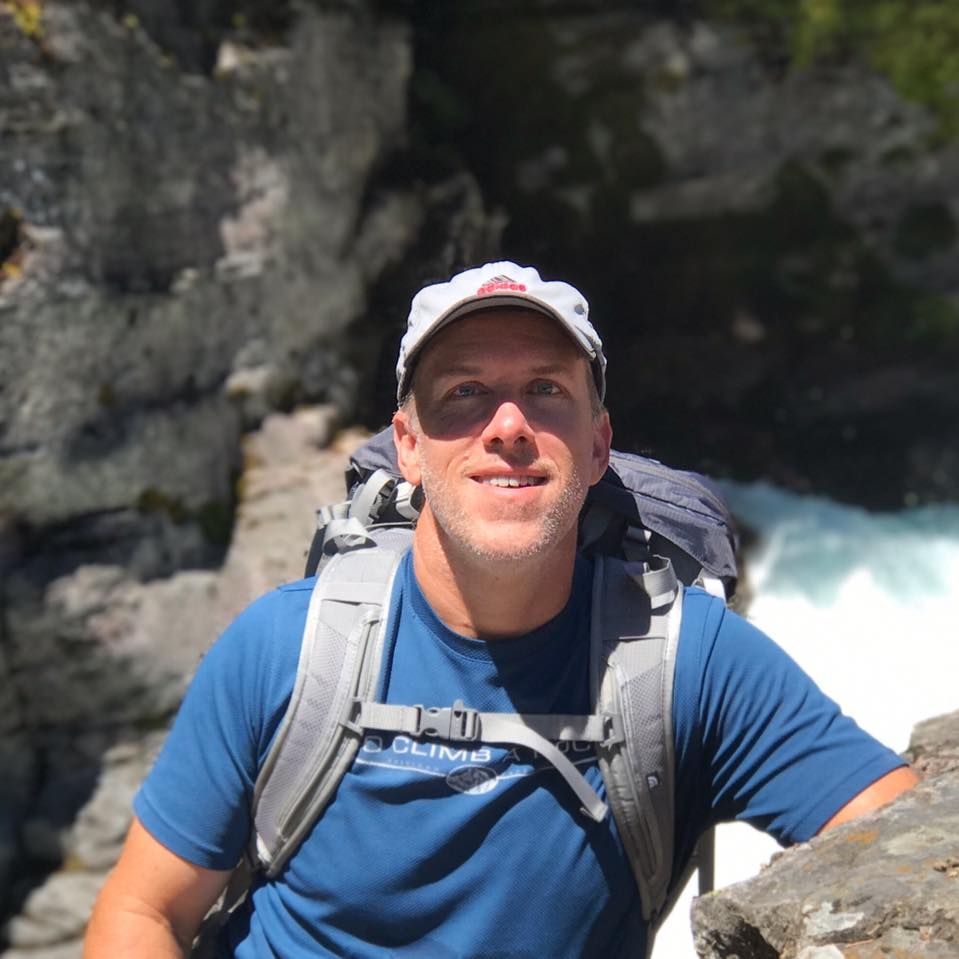 Rick Pittser, founder of QwestLyfe, hiking beside a mountain river
